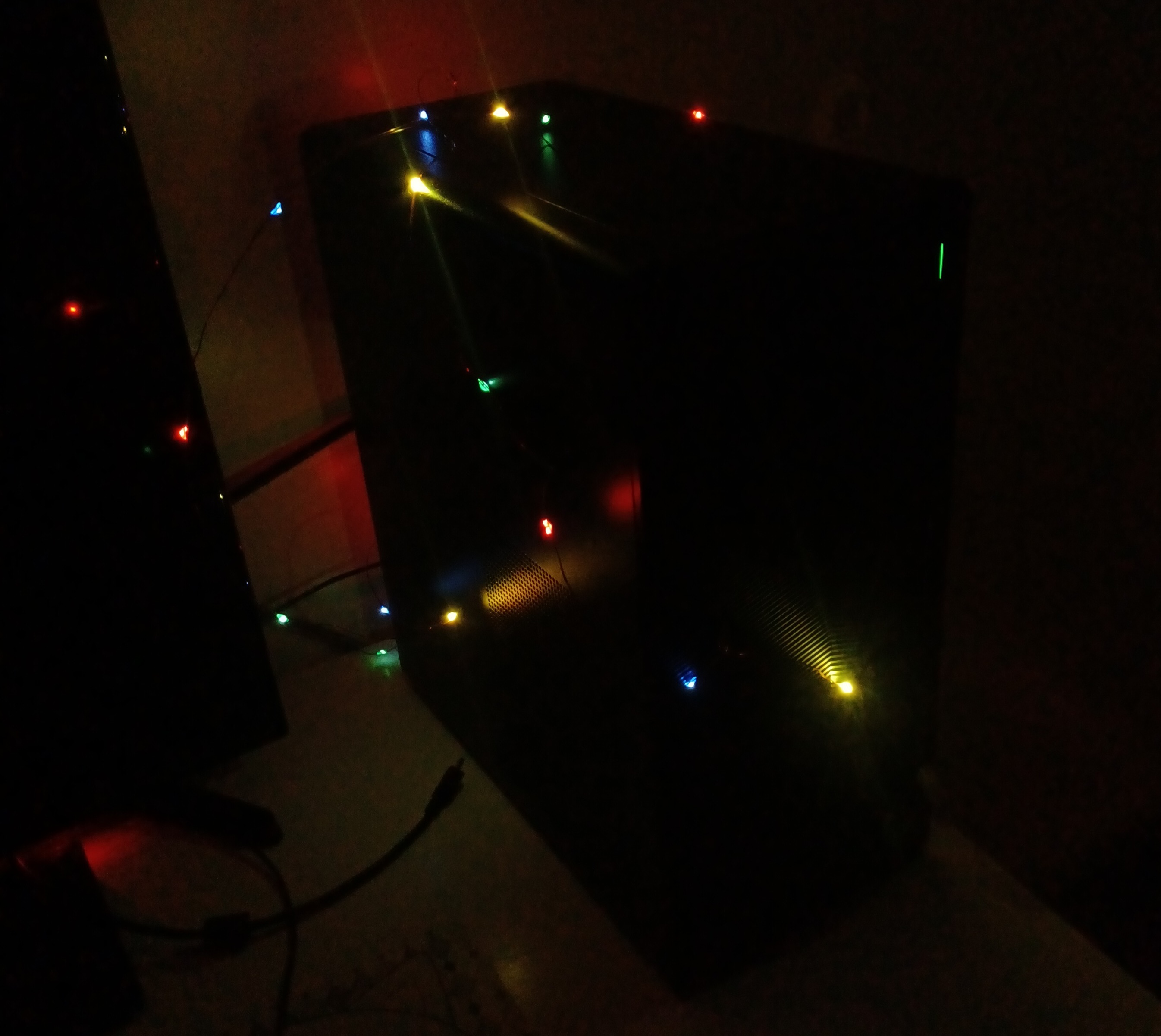 a photo of my desktop computer, tessa, with colorful lights strung around her.
